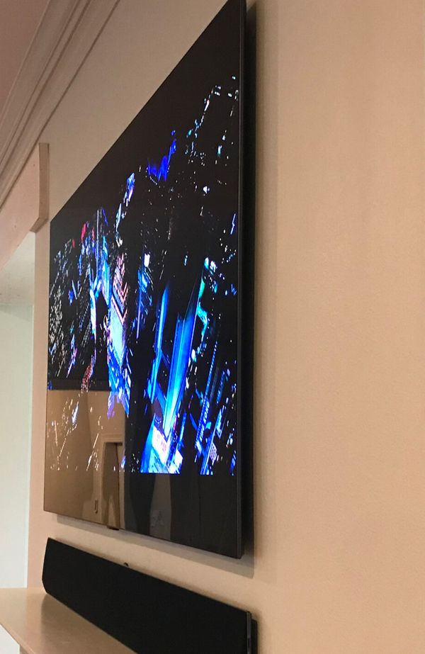 Side view of a TV mounted flat against the wall with a soundbar below