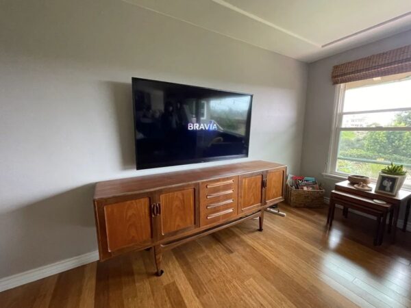 TV mounted over a mid-century credenza in a sunny living room